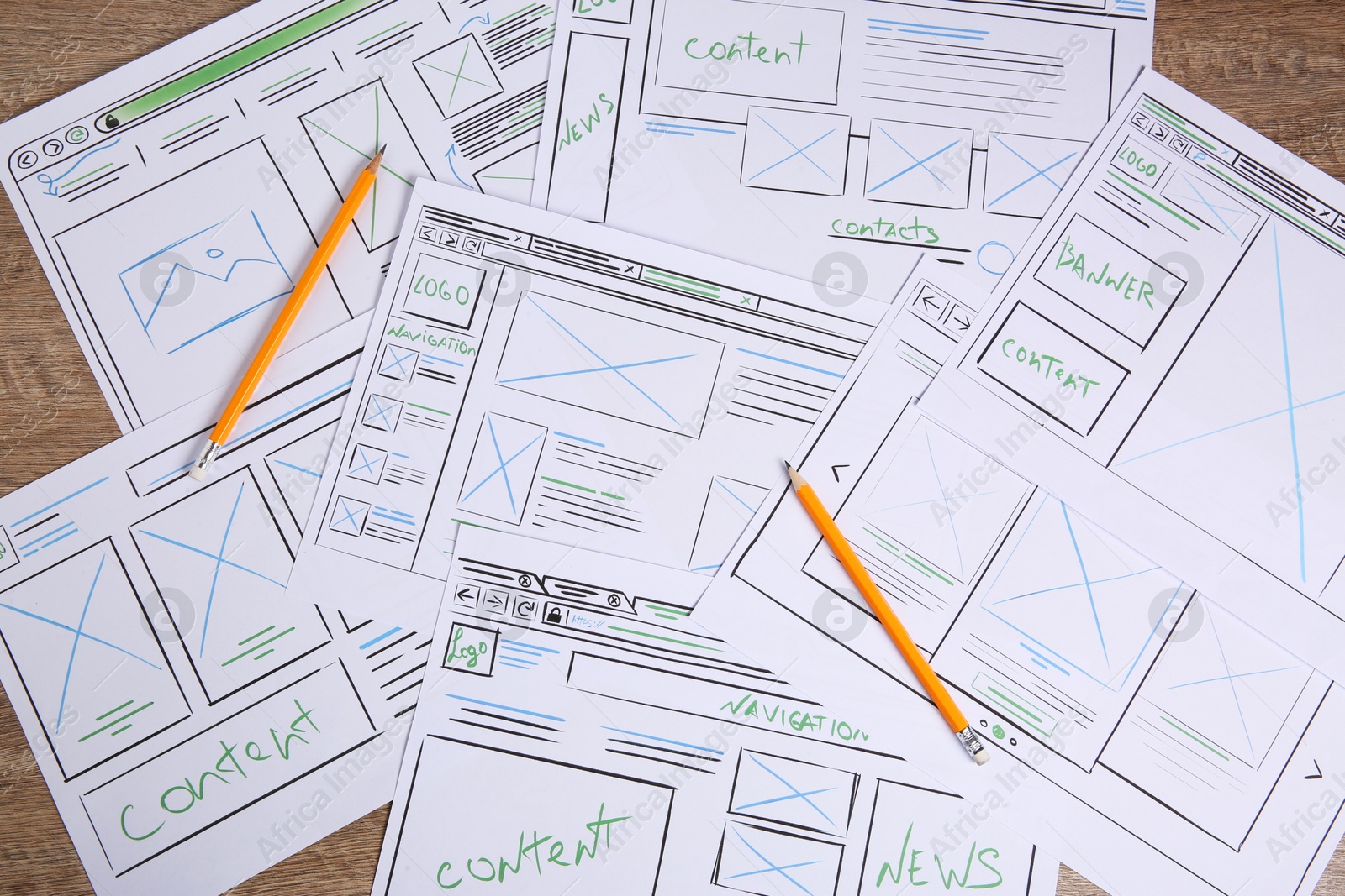 Photo of Developing UI design. Sketches of website wireframes and pencils on wooden table, top view