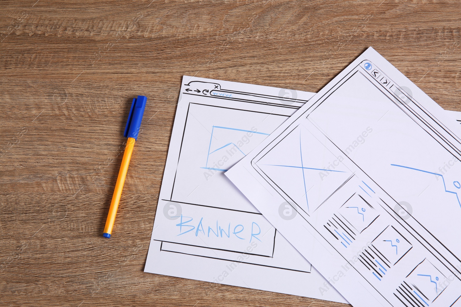 Photo of Developing UI design. Sketches of website wireframes and pen on wooden table, top view