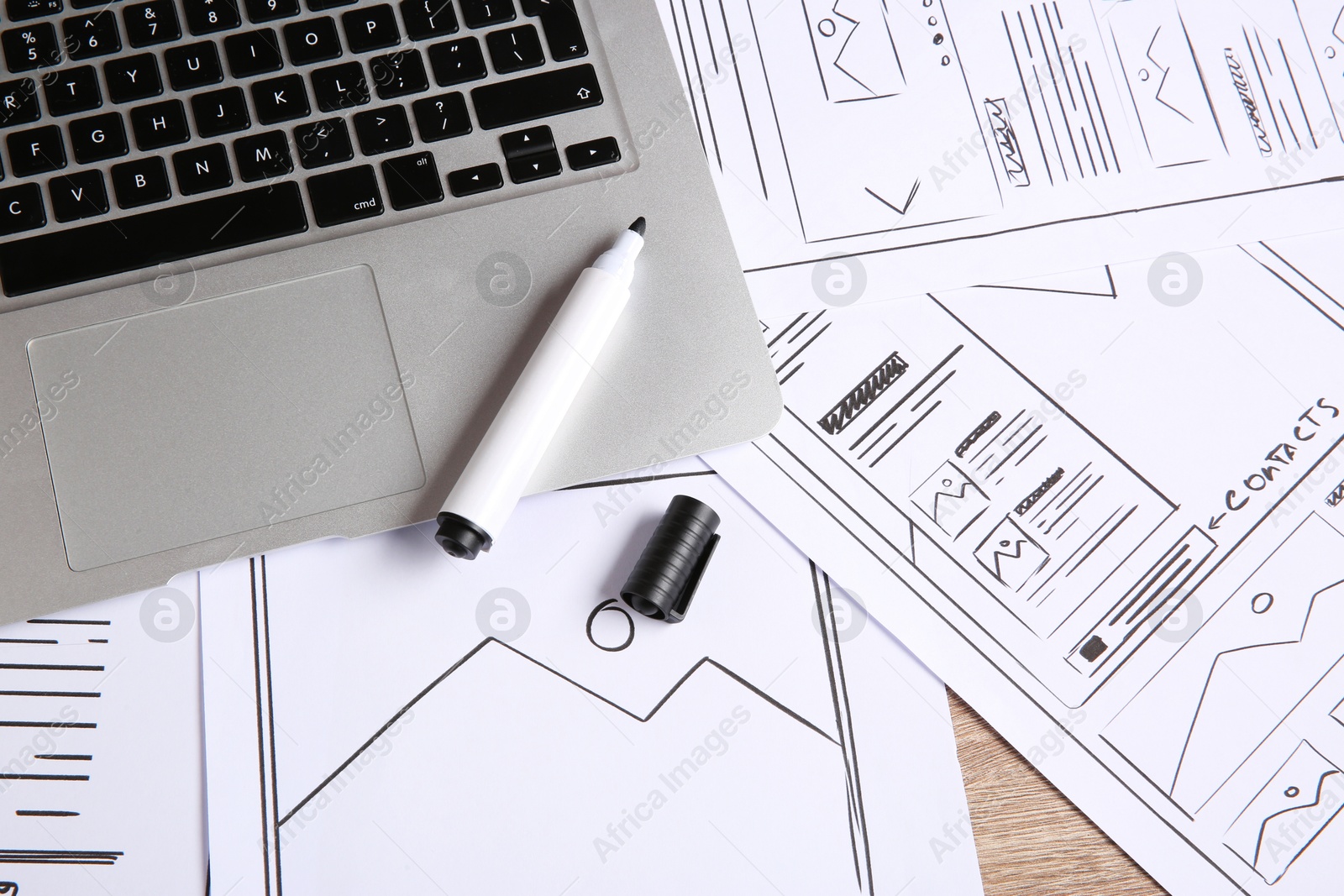 Photo of Developing UI design. Sketches of website wireframes, laptop and felt pen on wooden table, above view