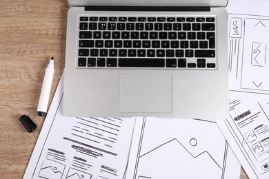 Photo of Developing UI design. Sketches of website wireframes, laptop and felt pen on wooden table, top view