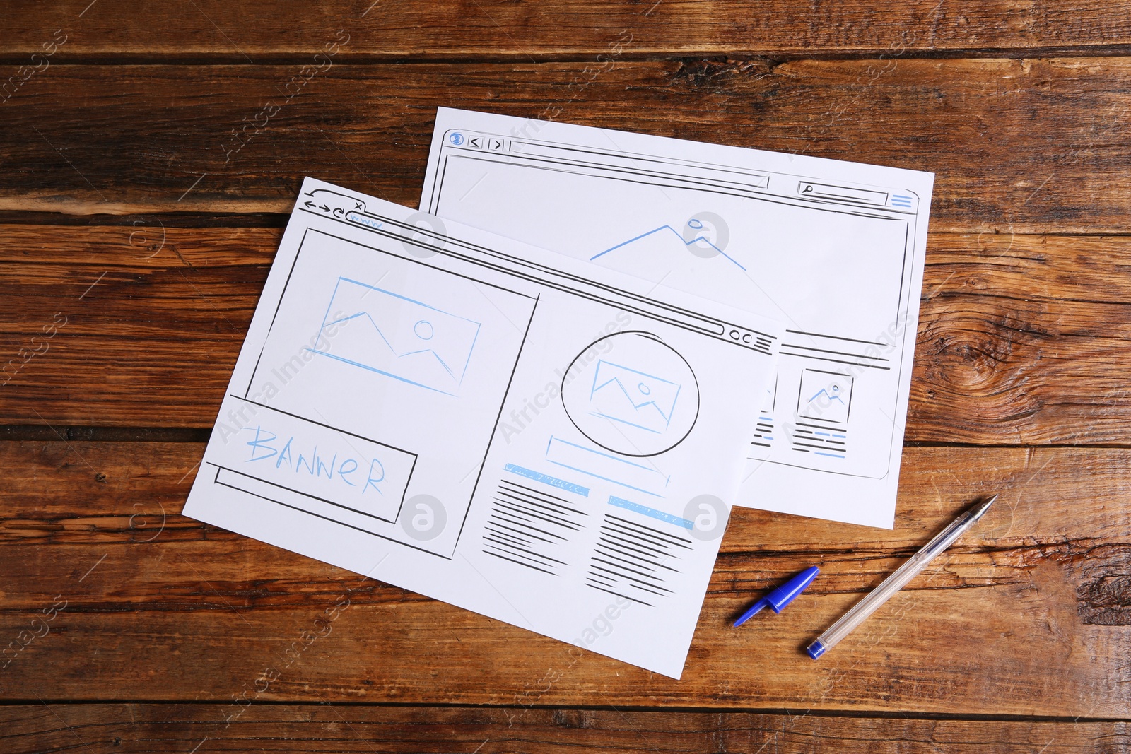 Photo of Developing UI design. Sketches of website wireframes and pen on wooden table, top view