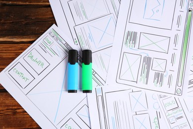 Photo of Developing UI design. Sketches of website wireframes and felt pens on wooden table, top view