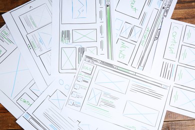 Photo of Developing UI design. Sketches of website wireframes on wooden table, top view