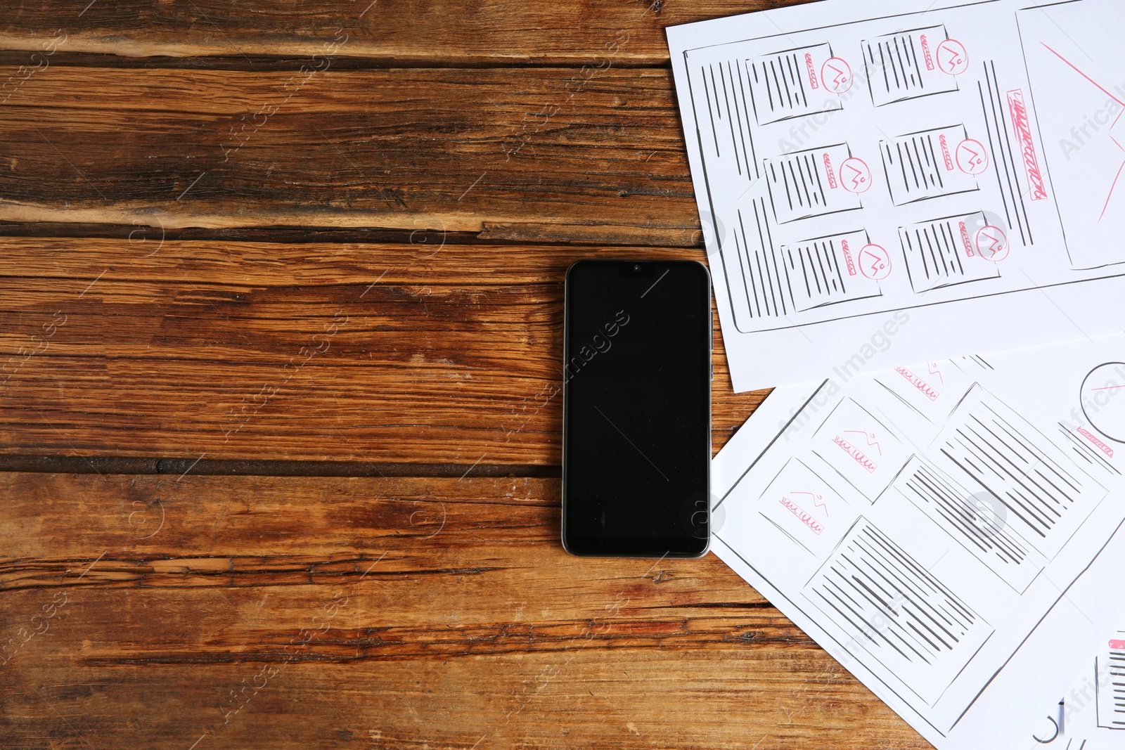 Photo of Developing UI design. Sketches of website wireframes and smartphone on wooden table, top view. Space for text