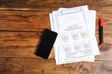 Photo of Developing UI design. Sketches of website wireframes, felt pen and smartphone on wooden table, top view. Space for text