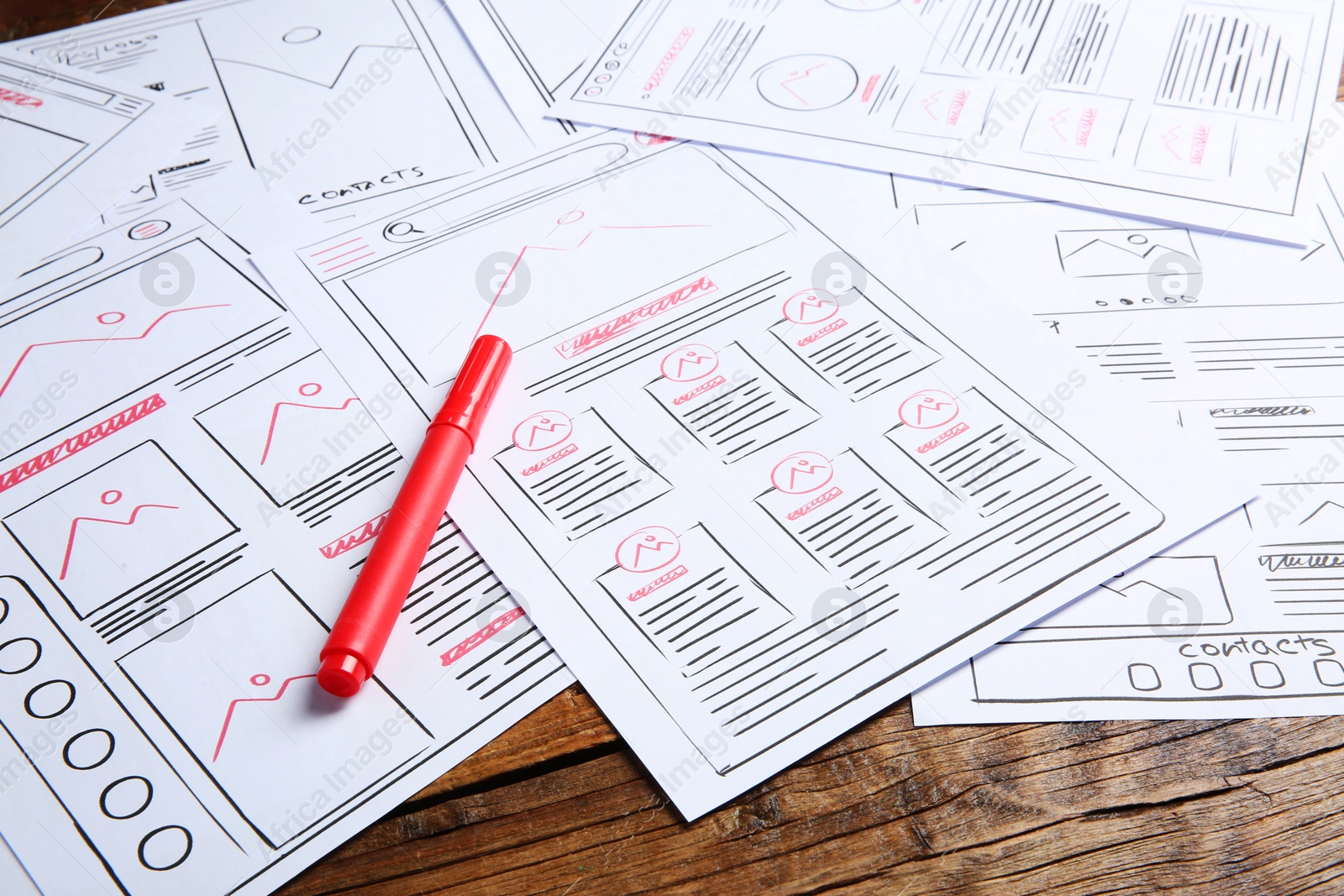 Photo of Developing UI design. Sketches of website wireframes and felt pen on wooden table, closeup