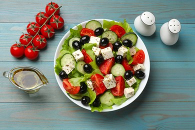 Photo of Delicious salad with feta cheese served on light blue wooden table, flat lay