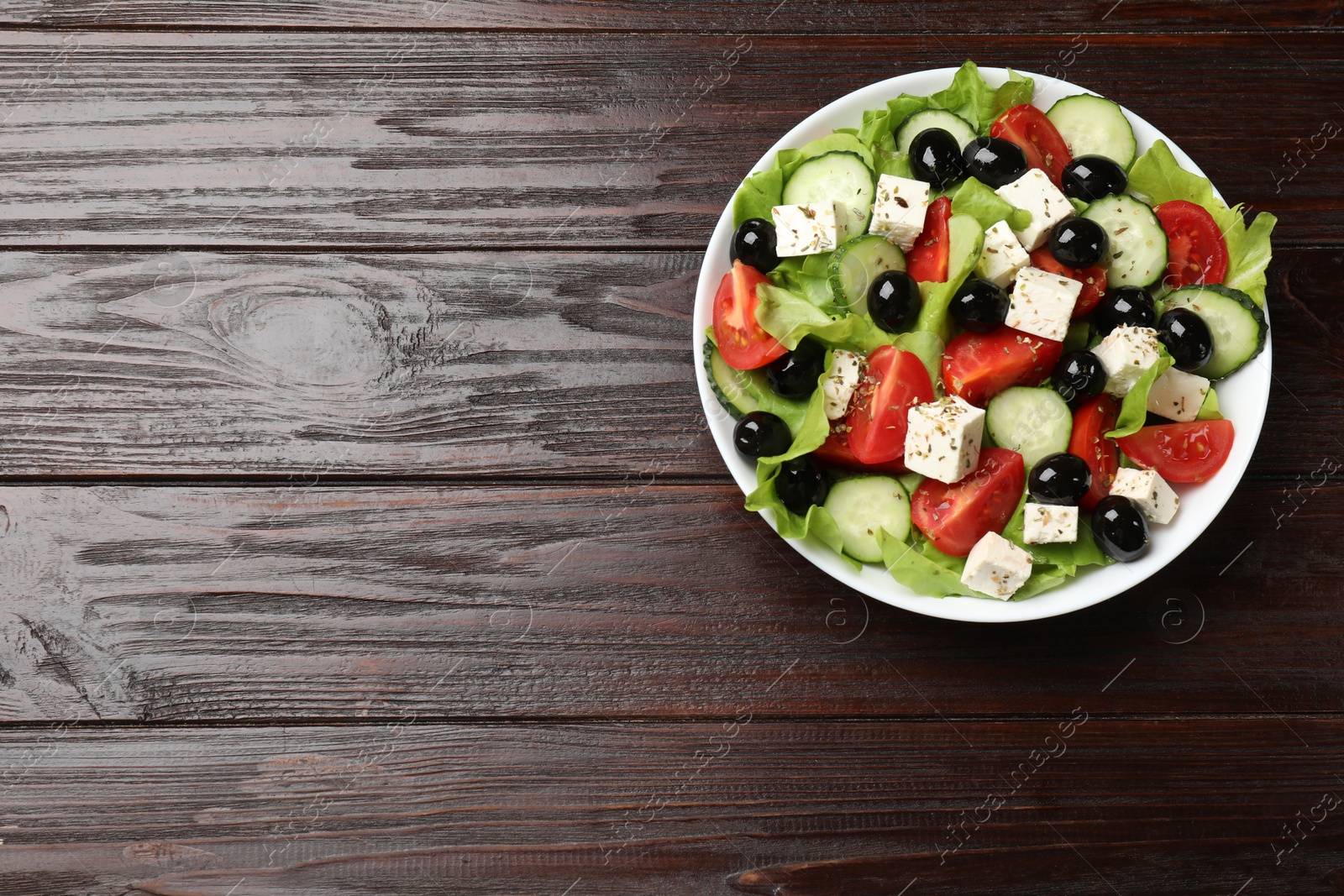 Photo of Delicious salad with feta cheese on wooden table, top view. Space for text