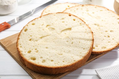 Photo of Delicious cut sponge cake and knife on white wooden table