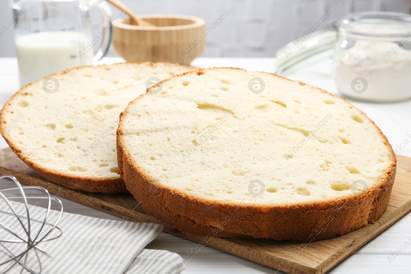 Photo of Delicious cut sponge cake on white wooden table