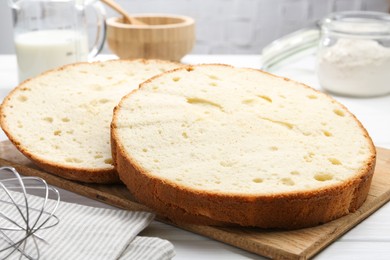 Photo of Delicious cut sponge cake on white wooden table