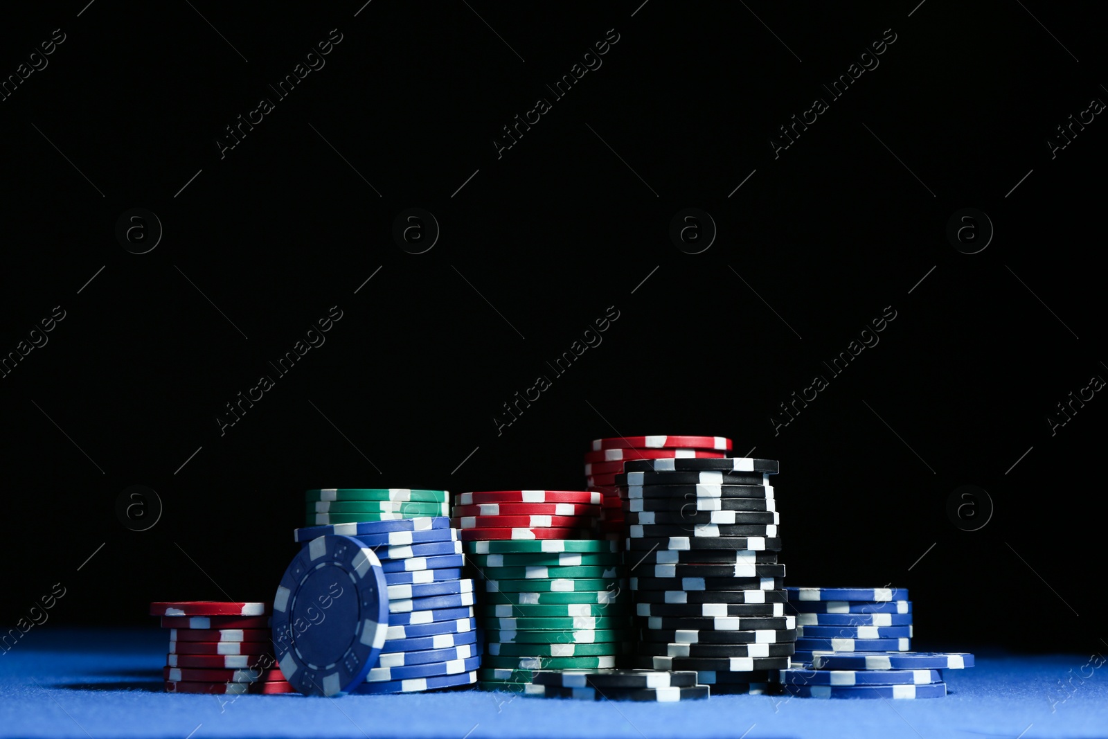 Photo of Poker game. Casino chips on blue table against dark background, space for text