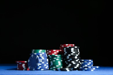 Poker game. Casino chips on blue table against dark background, space for text