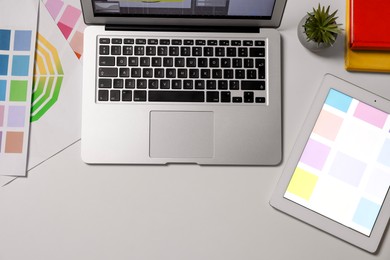 Photo of Designer's workplace with tablet, laptop and palettes on white table, flat lay