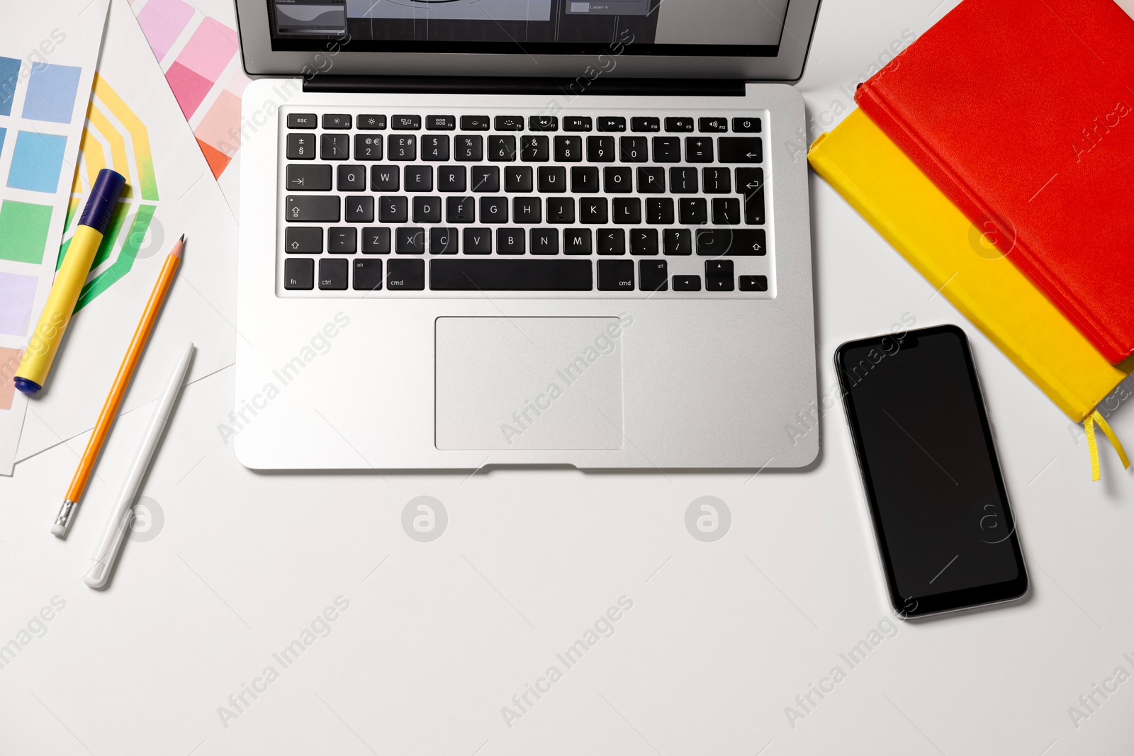 Photo of Designer's workplace with laptop, smartphone, stationery and palettes on white table, flat lay