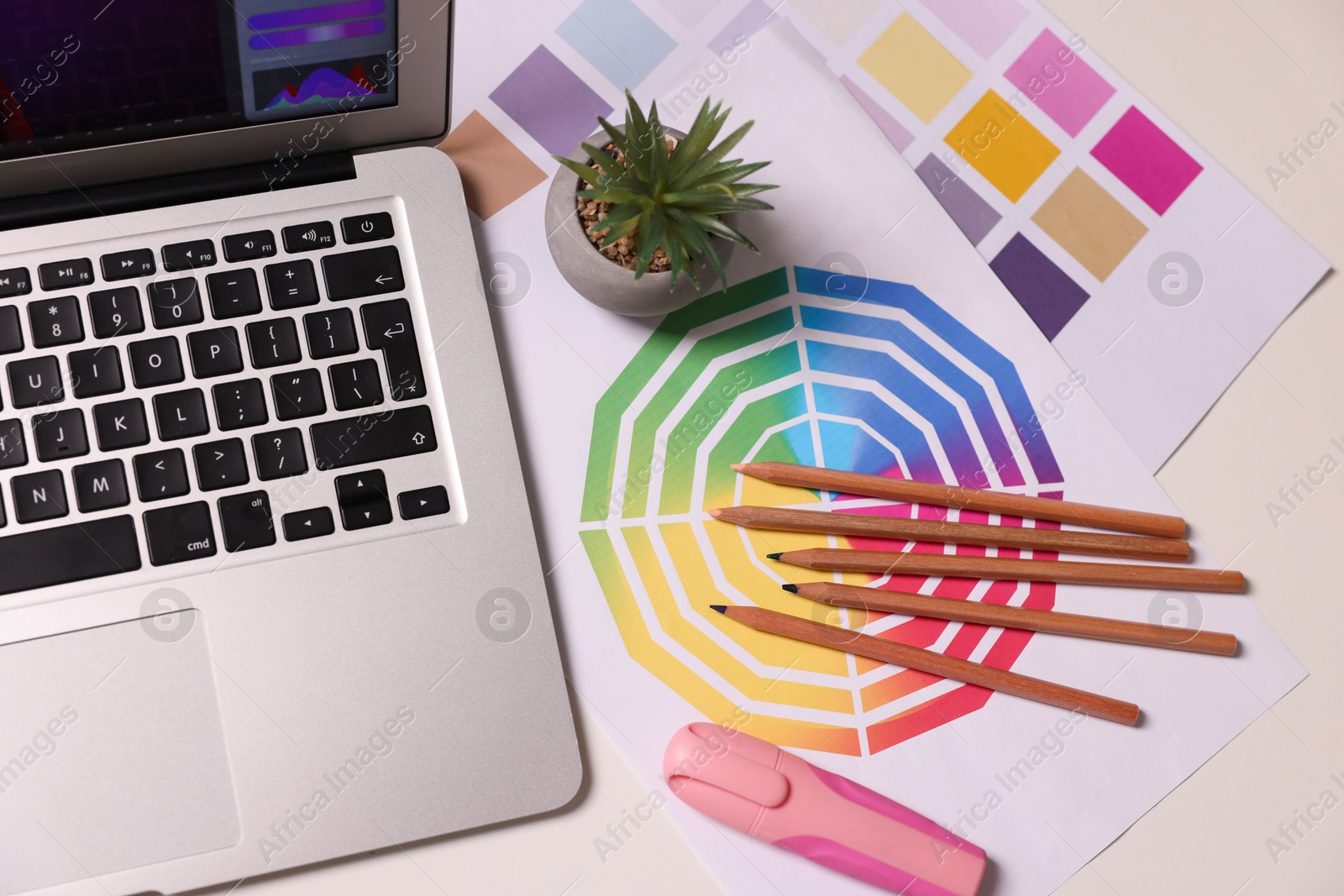 Photo of Designer's workplace with laptop, stationery and palettes on white table, flat lay