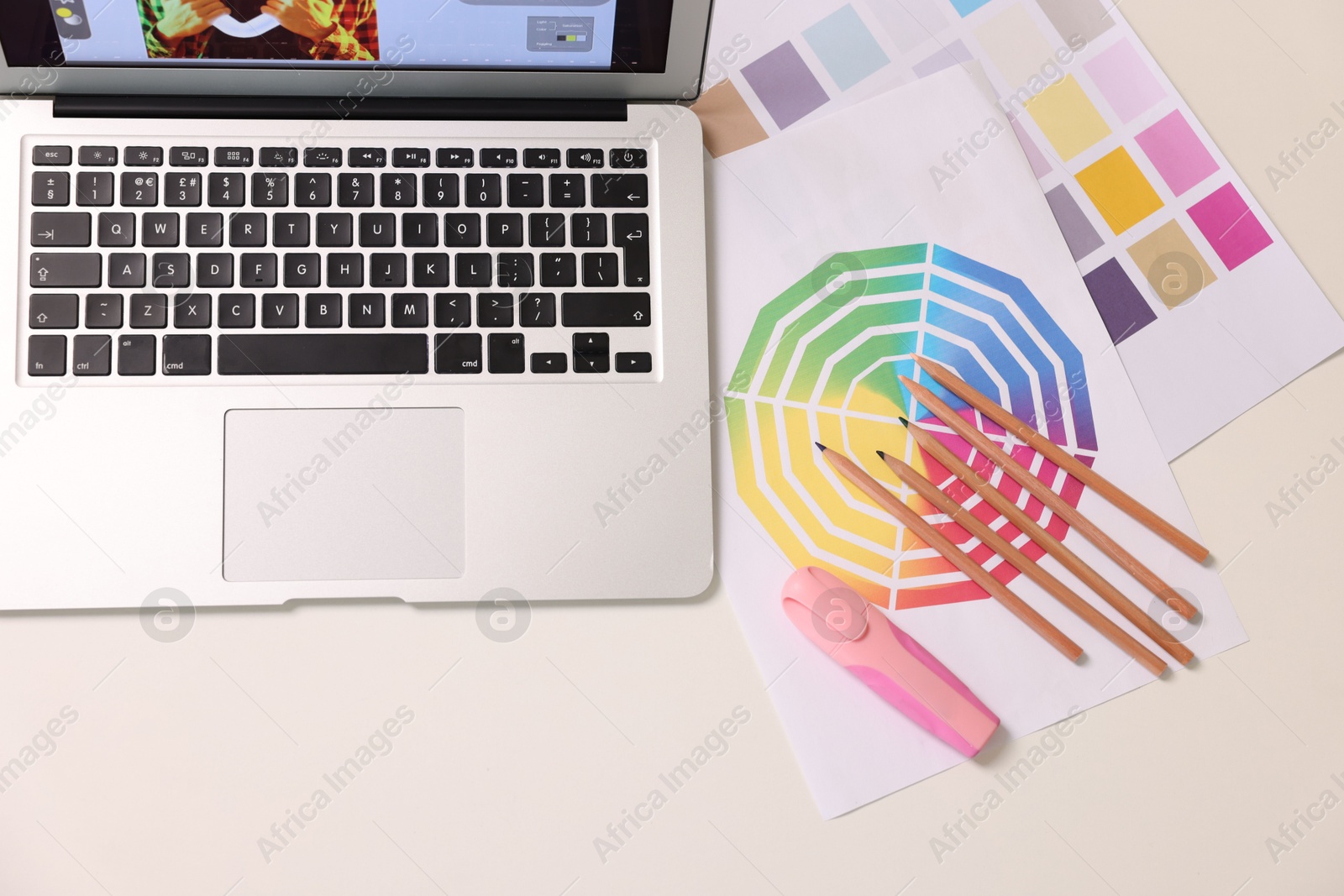 Photo of Designer's workplace with laptop, stationery and palettes on white table, flat lay