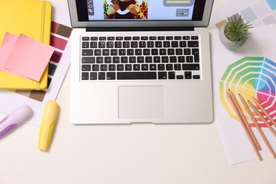 Photo of Designer's workplace with laptop, stationery and palettes on white table, flat lay