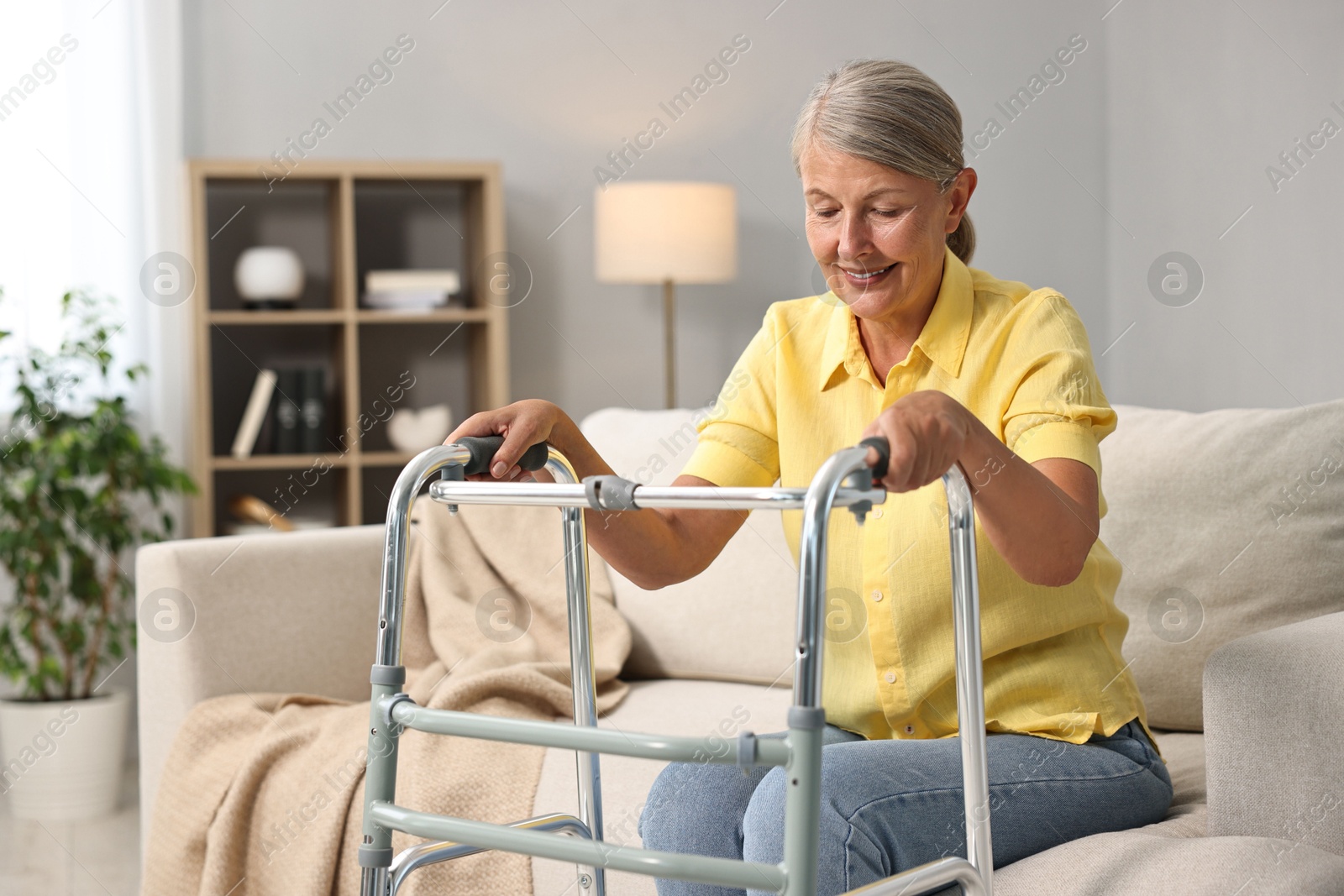 Photo of Senior woman with walking frame on sofa at home