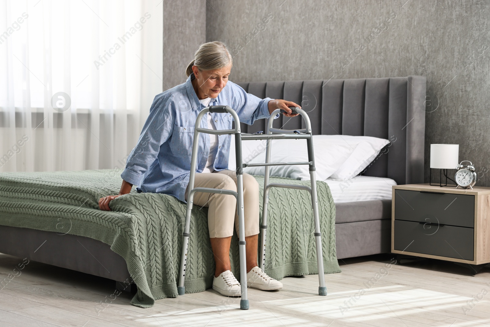 Photo of Senior woman with walking frame on bed at home