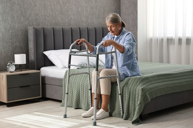 Photo of Senior woman with walking frame on bed at home