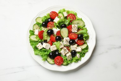 Photo of Delicious salad with feta cheese and ingredients on white table, top view