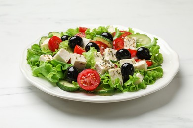 Photo of Delicious salad with feta cheese and ingredients on white table, closeup