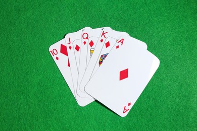 Photo of Poker game. Playing cards on green table, top view