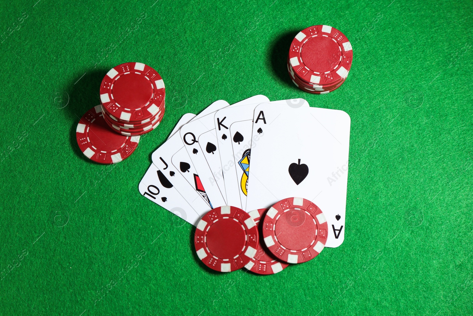 Photo of Playing cards and poker chips on green table, flat lay