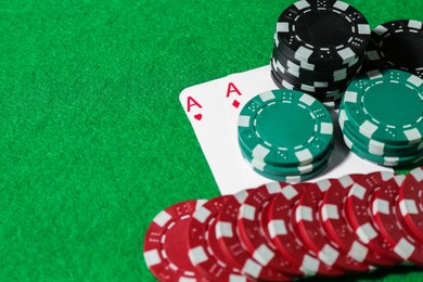 Photo of Playing cards and poker chips on green table, closeup. Space for text