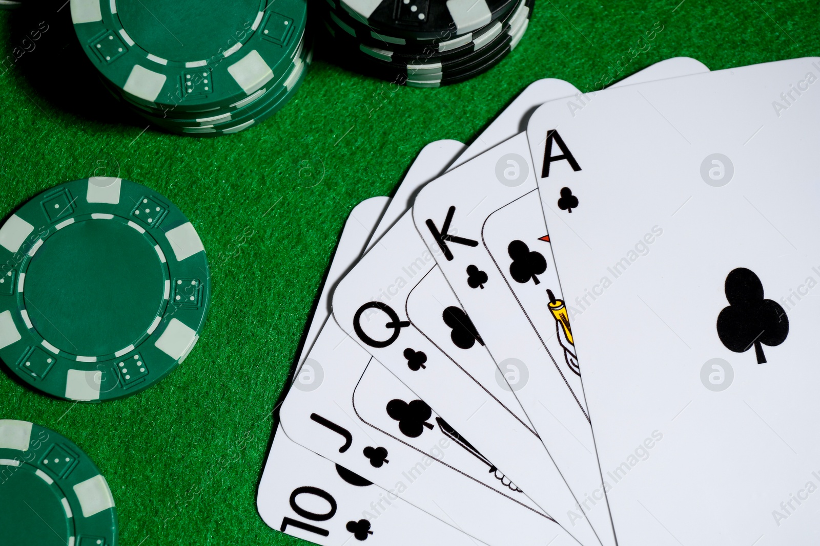 Photo of Playing cards and poker chips on green table, flat lay