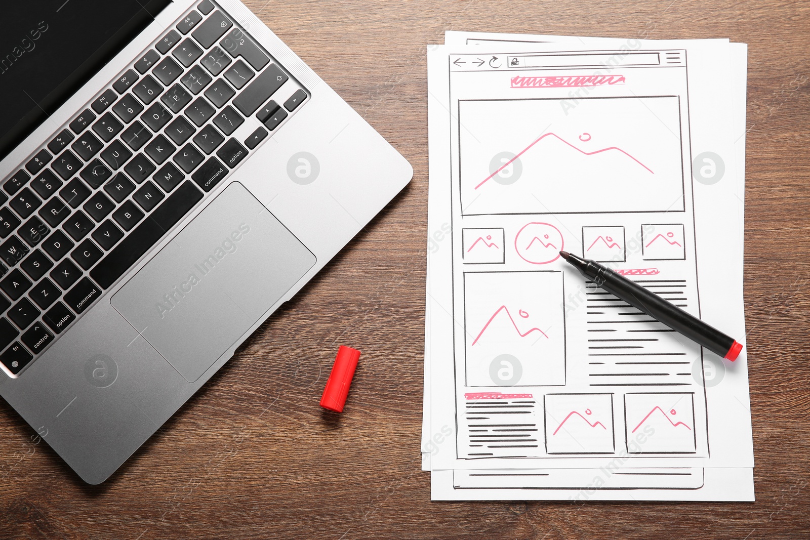 Photo of Developing UI design. Sketches of website wireframes, felt pen and laptop on wooden table, top view