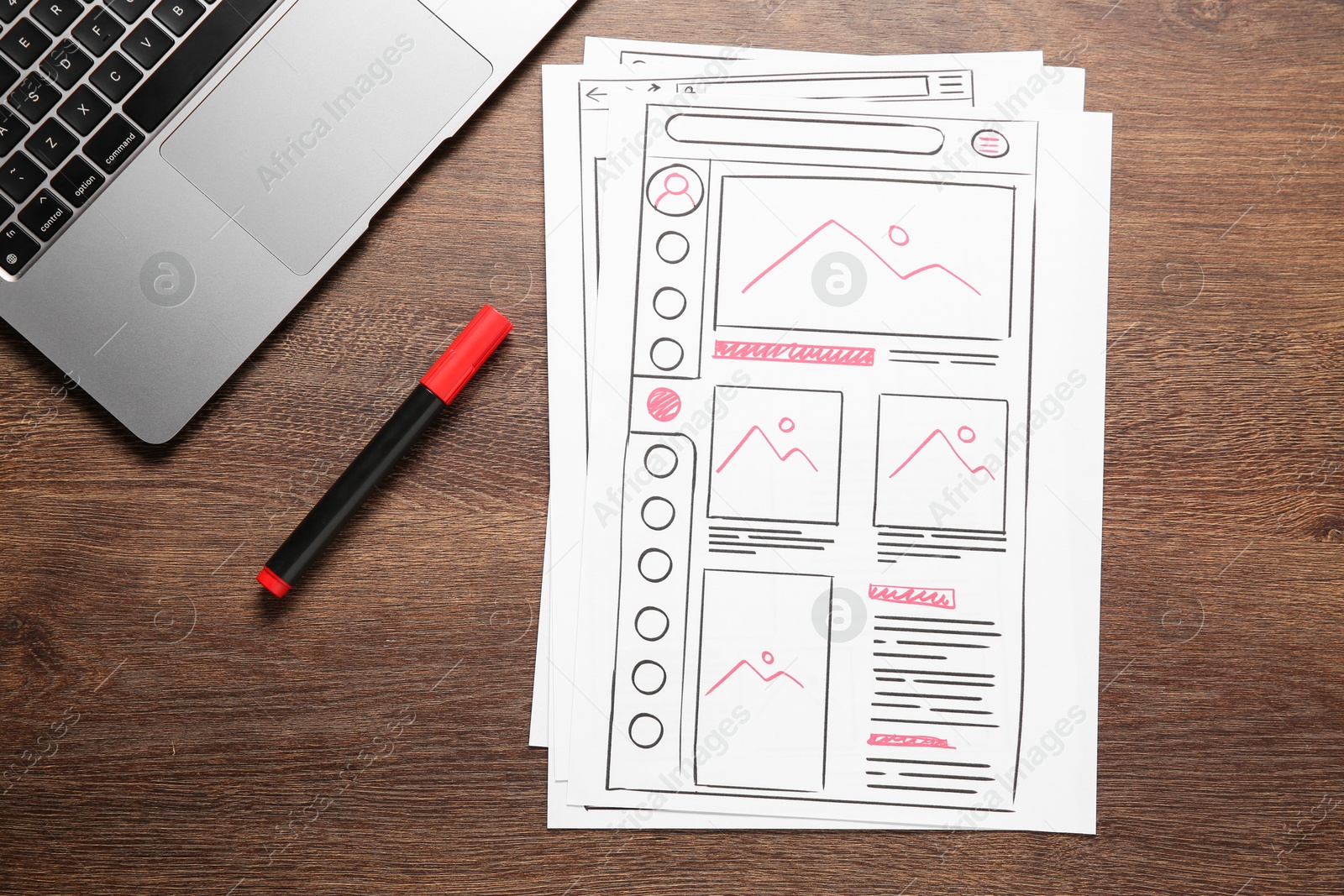 Photo of Developing UI design. Sketches of website wireframes, felt pen and laptop on wooden table, top view