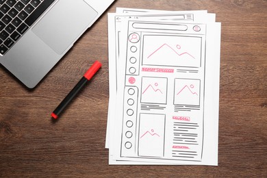 Photo of Developing UI design. Sketches of website wireframes, felt pen and laptop on wooden table, top view