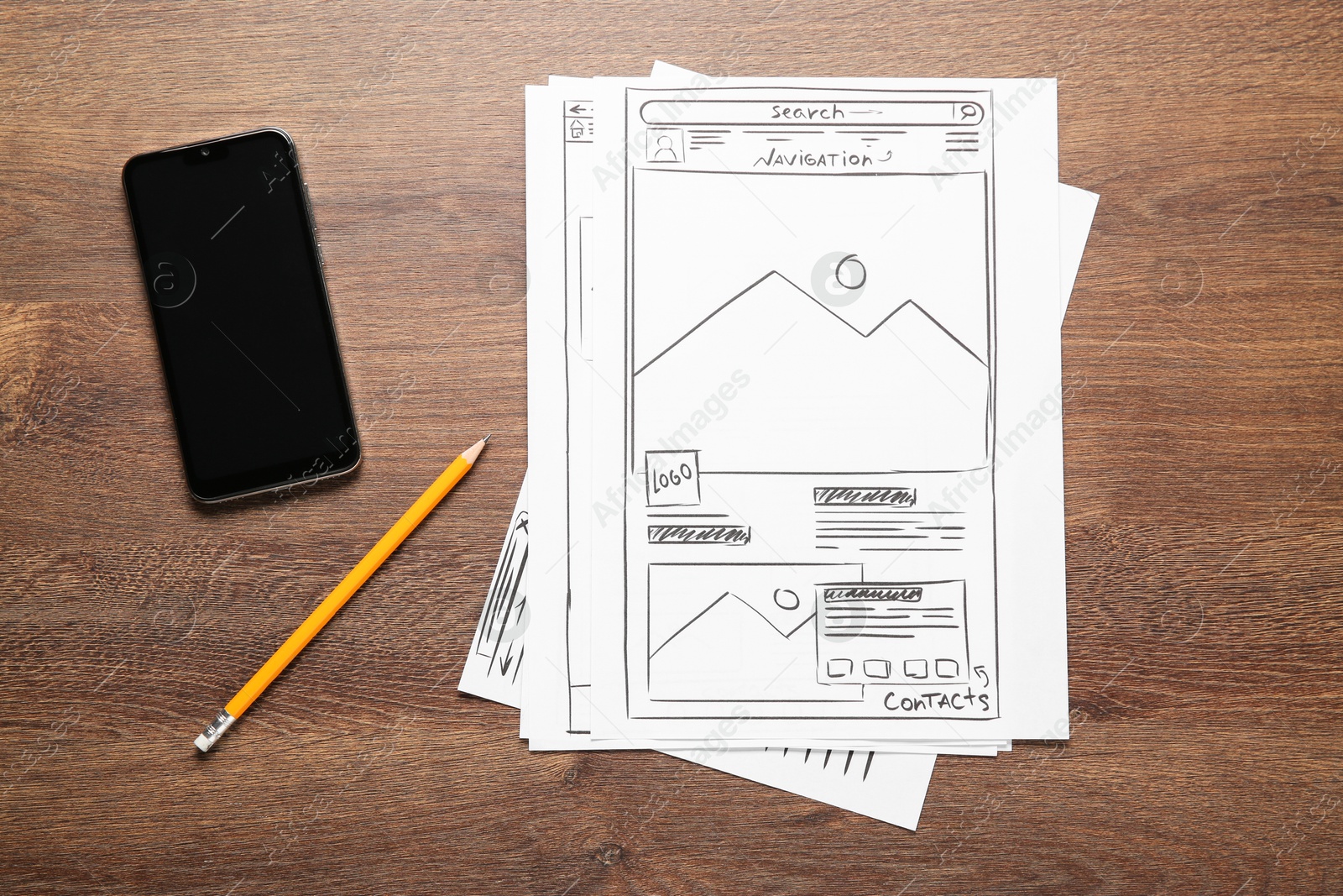 Photo of Developing UI design. Sketches of website wireframes, pencil and smartphone on wooden table, top view