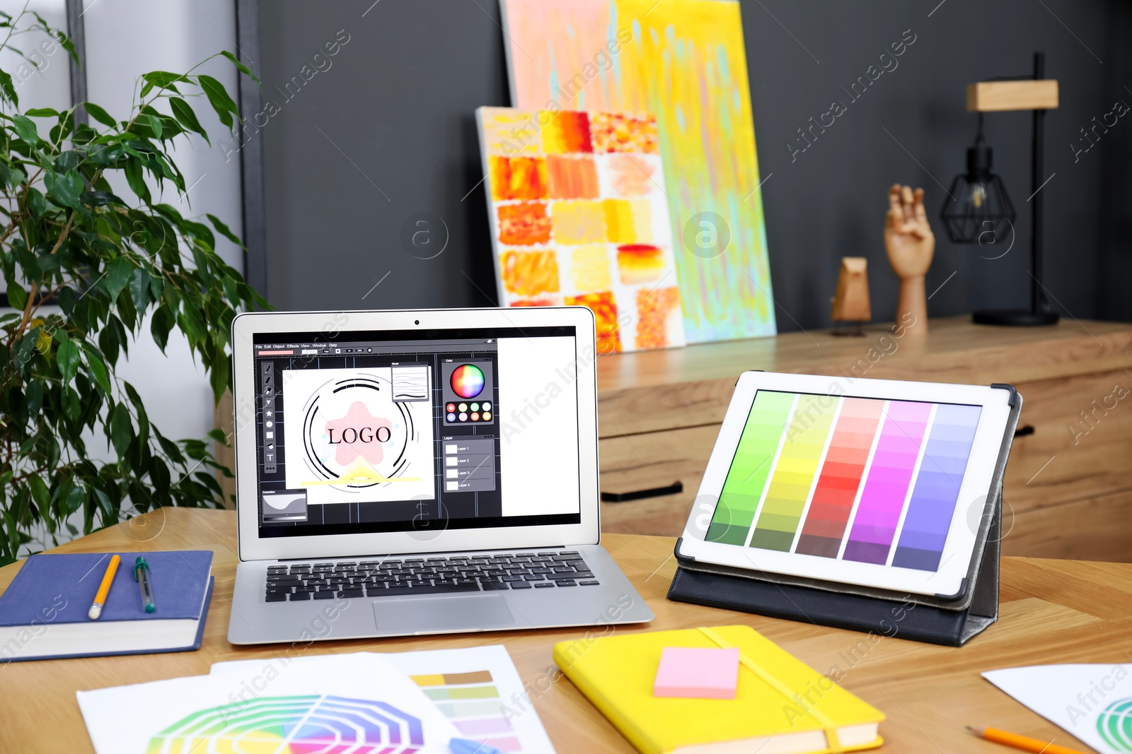 Photo of Designer's workplace with laptop, tablet, stationery and palettes on wooden table indoors