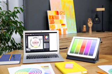 Photo of Designer's workplace with laptop, tablet, stationery and palettes on wooden table indoors