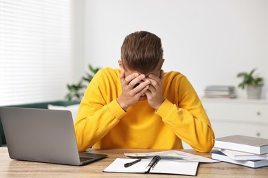 Photo of Tired student having stress before exam at table indoors