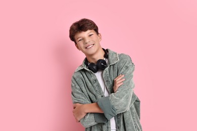 Photo of Happy teenage boy with headphones on pink background