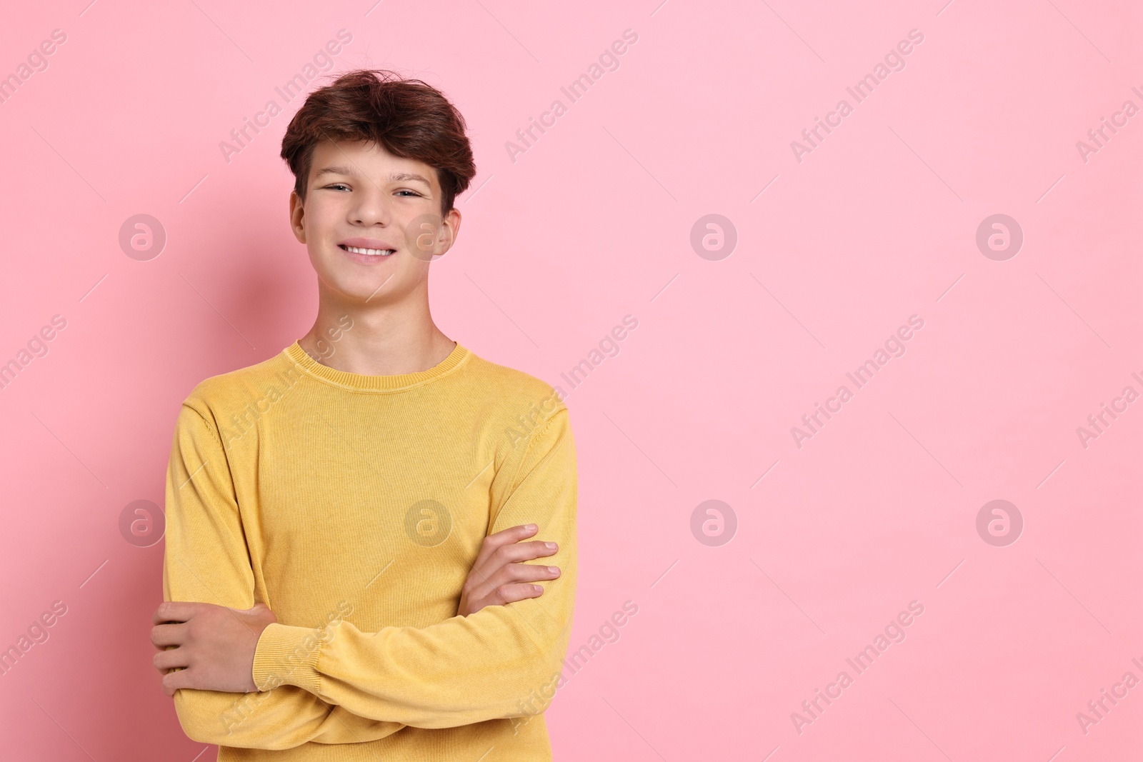 Photo of Portrait of happy teenage boy on pink background, space for text