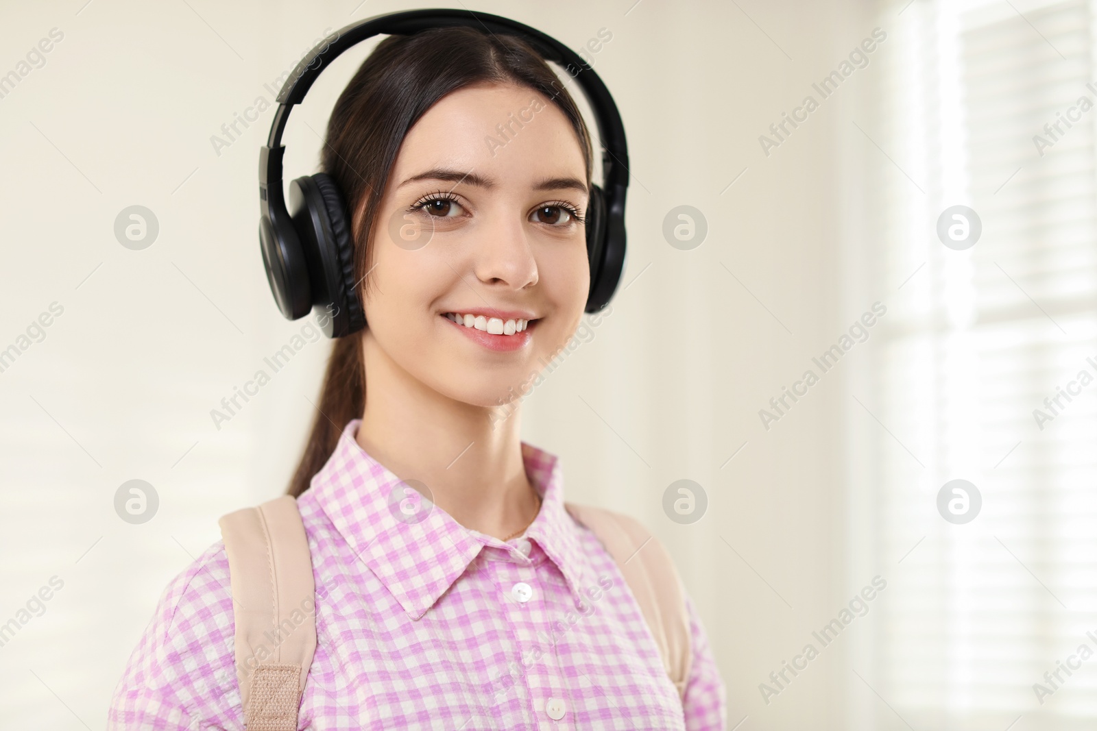 Photo of Portrait of smiling teenage girl in headphones at home. Space for text