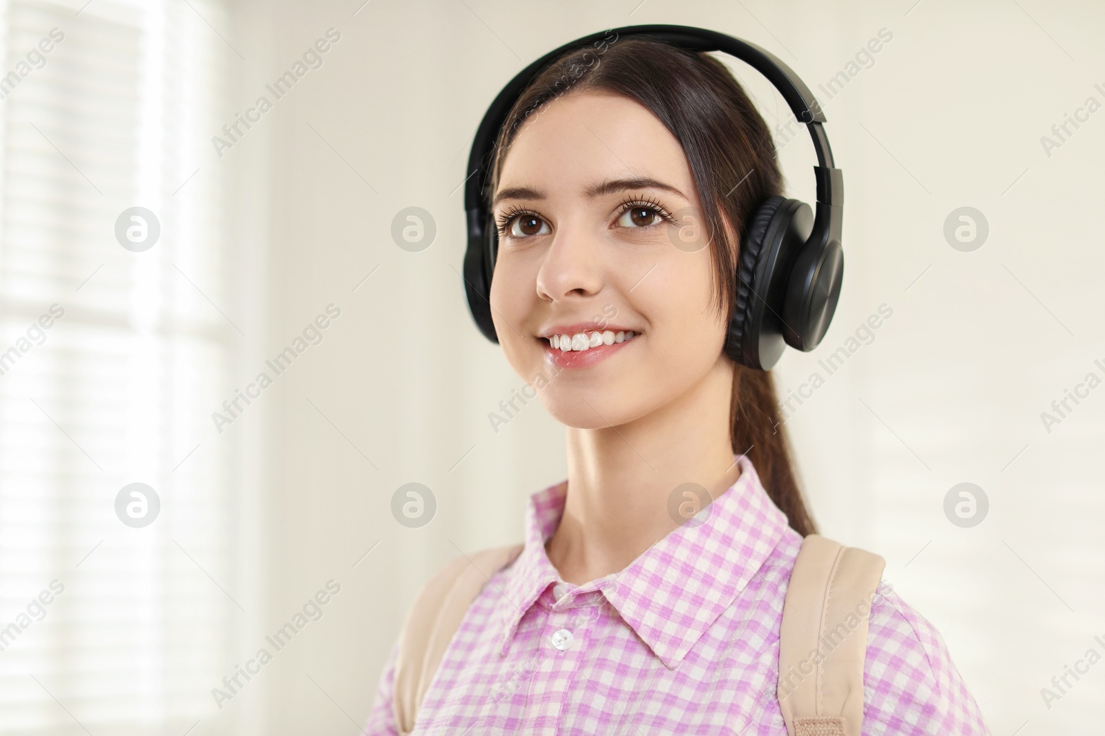 Photo of Portrait of smiling teenage girl in headphones at home