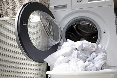 Photo of Basket with laundry near open washing machine