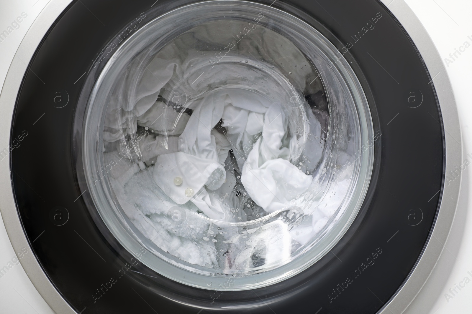 Photo of Washing machine with clothes as background, closeup