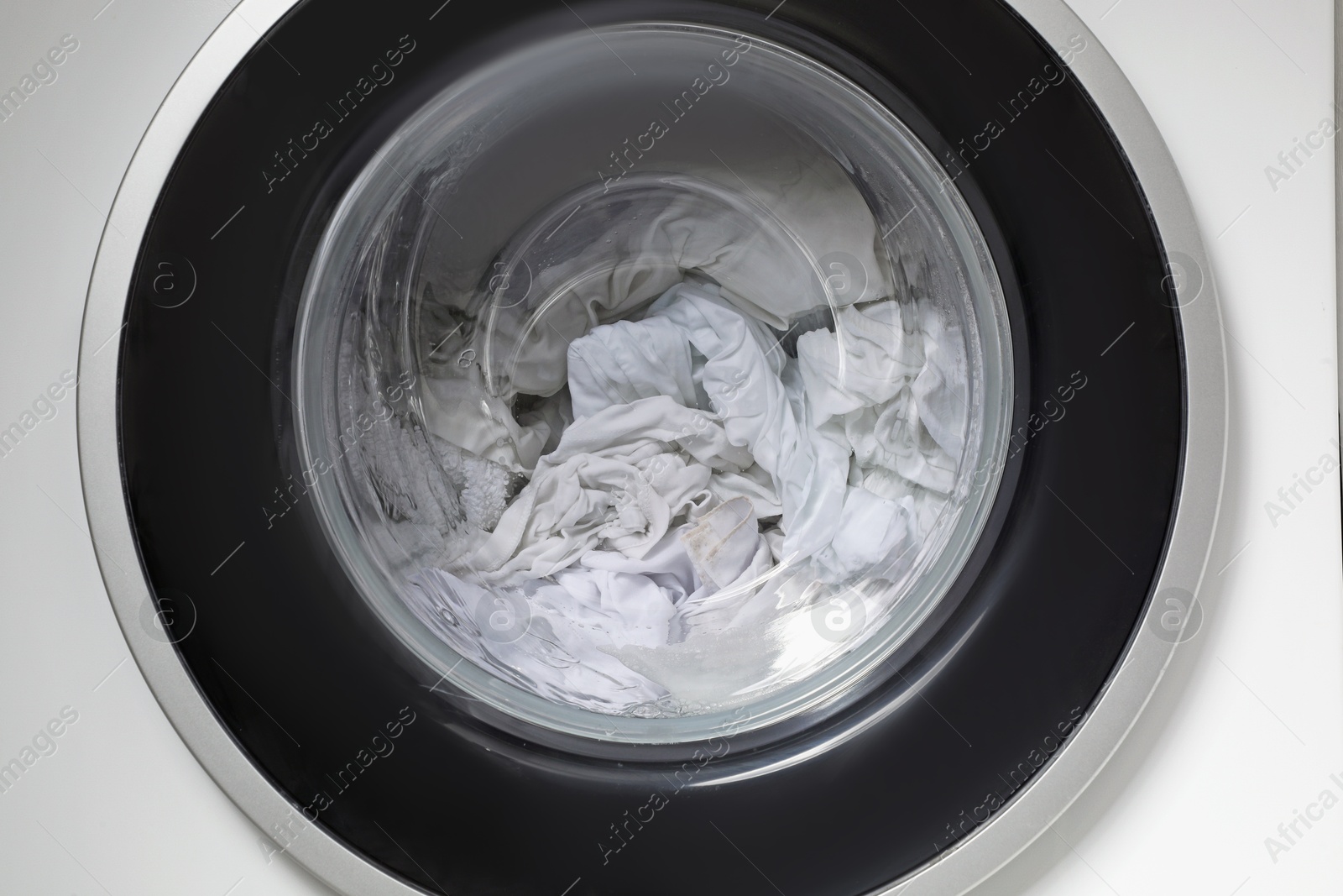 Photo of Washing machine with clothes as background, closeup