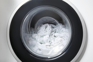 Photo of Washing machine with clothes as background, closeup