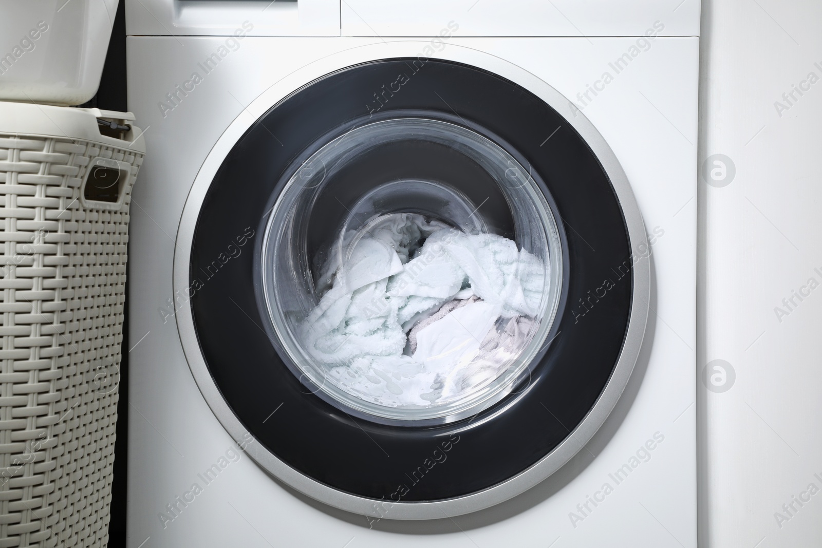 Photo of Washing machine with clothes as background, closeup