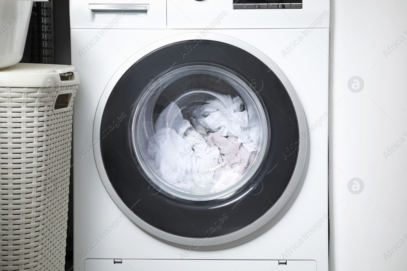 Photo of Washing machine with clothes as background, closeup