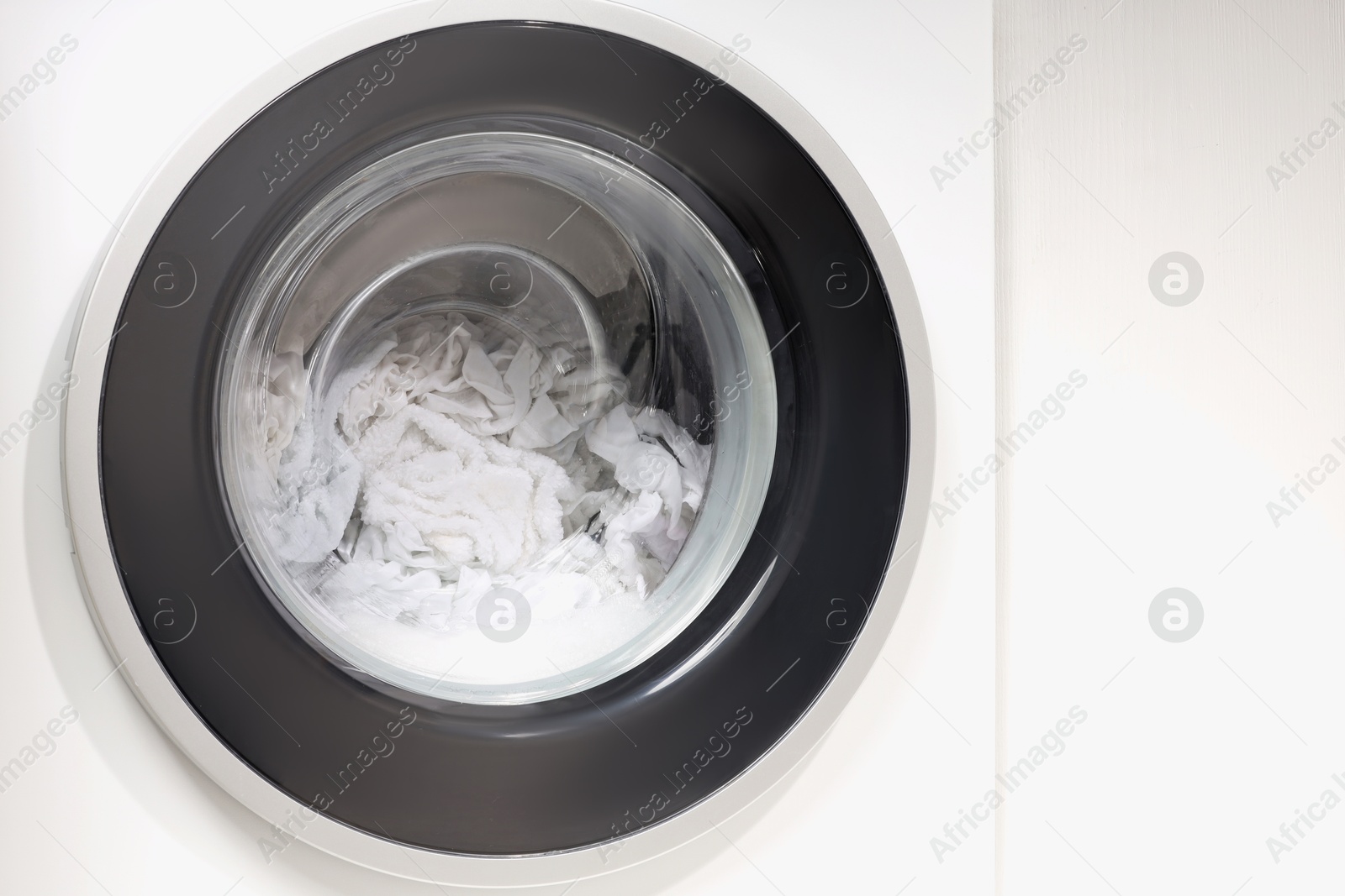 Photo of Washing machine with clothes as background, closeup