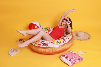 Photo of Beautiful woman in swimsuit with beach accessories on yellow background